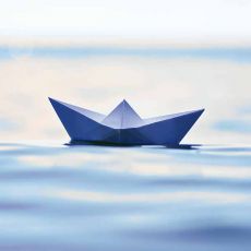 Symbolbild Papierschiff auf Wasser