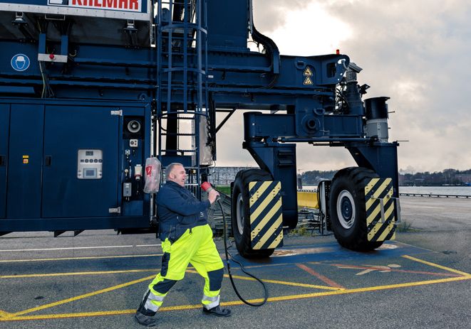 Employee of the PORT OF KIEL with cable in hand in front of a crane